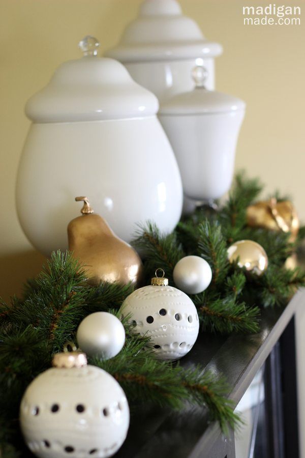 Lovely white ornaments mixed with evergreens - part of the holiday home tour at madiganmade.com